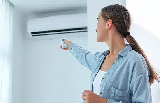 femme actionnant la télécommande d'une climatisation