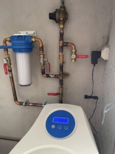 Installation d'un adoucisseur d'eau dans un garage avec vue sur les tuyaux