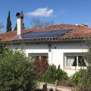 Vue d'un toit de maison où sont installés des panneaux photovoltaïques à côté d'une cheminée