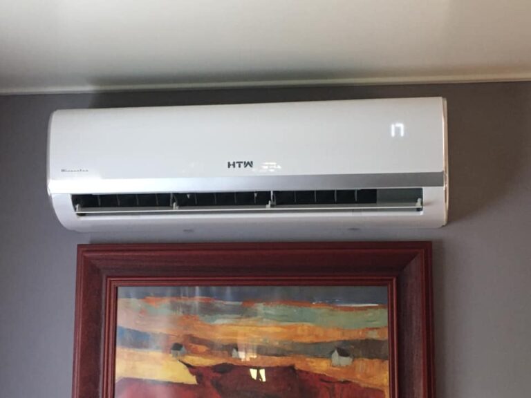 Module intérieur d'une climatisation réversible, installé sur un mur, au-dessus d'un tableau.